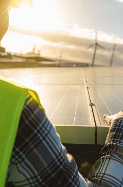 Young female engineer working for alternative energy with wind turbine and photovoltaic solar panel